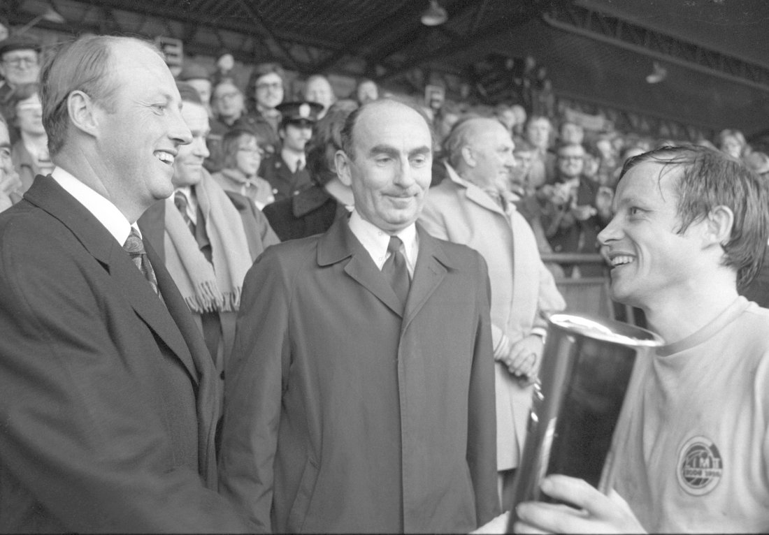 Oslo 19751026.Fotball, cupfinalen Bodø/Glimt - Vard 2-0, Ullevaal Stadion. Bodø/Glimts kaptein Harald Berg tar imot pokalen av kronprins Harald. I midten fotballpresident Einar Jørum.Foto Arild Hordnes / NTB / NTB