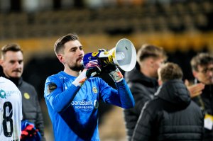 Nikita Haikin i blå keeperdrakt med megafon i hånden etter 5-0-seieren på Åråsen i april 2024. Sammen med lagkameratene feiret han tre poeng med supporterne. 