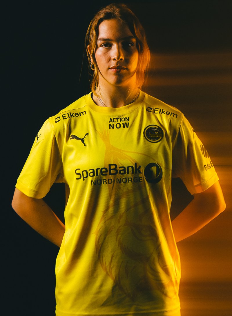 Lærke Hammer poserer i Bodø/Glimts nye hjemmedrakt for sesongen 2024 med et gult lys fra høyre side i bildet