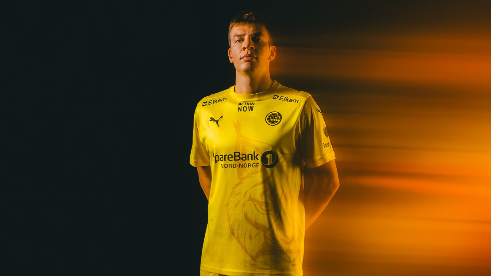 Bodø/Glimt-spiller Jostein Gundersen poserer i Glimts nye hjemmedrakt for 2024-sesongen i et svakt gult lys
