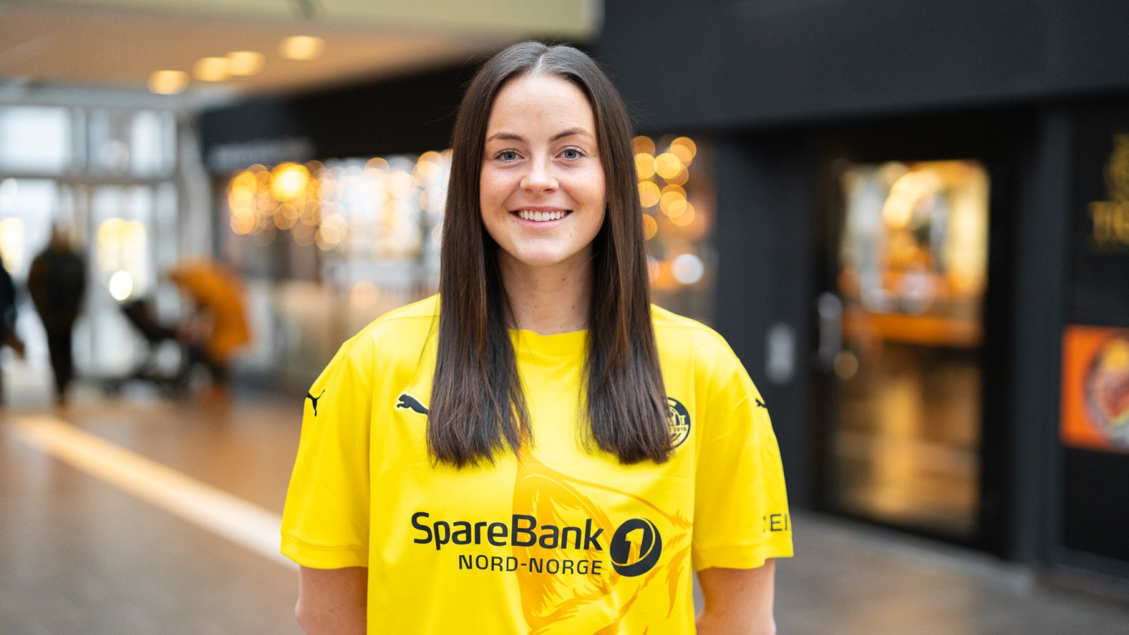 Avery Snead poserer med Glimt-drakten i midten av Glasshuset januar 2025.