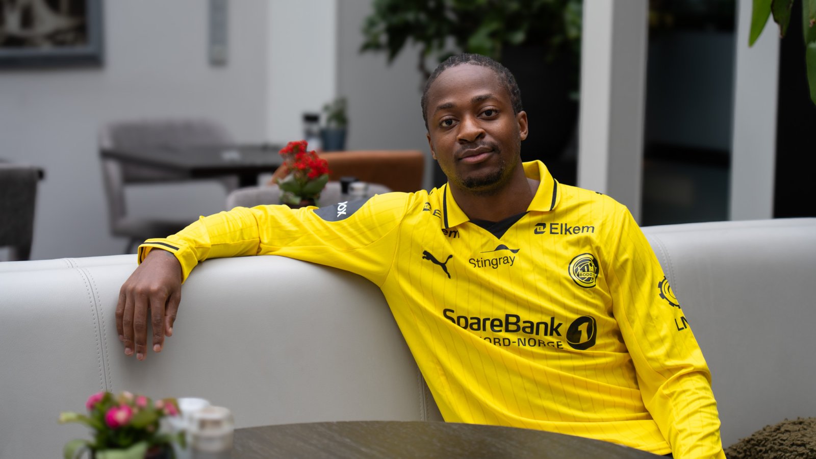 Joel Mvuka sitter på en sofa og ser inn i kamera i forbindelse med lanseringen. 