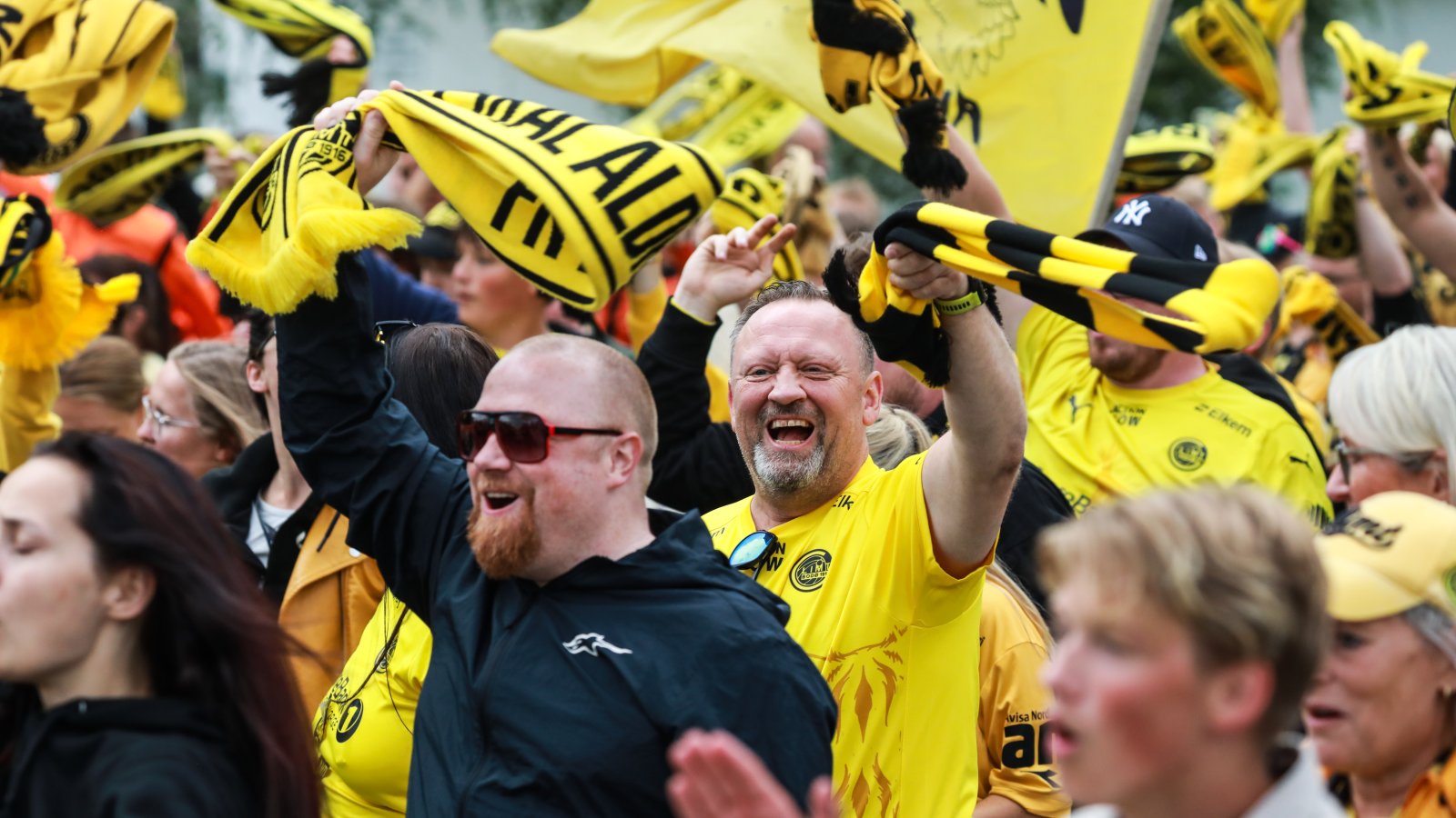 Mange Glimt-supportere jubler mens de heier på Bodø/Glimt med flagg og skjerf. 