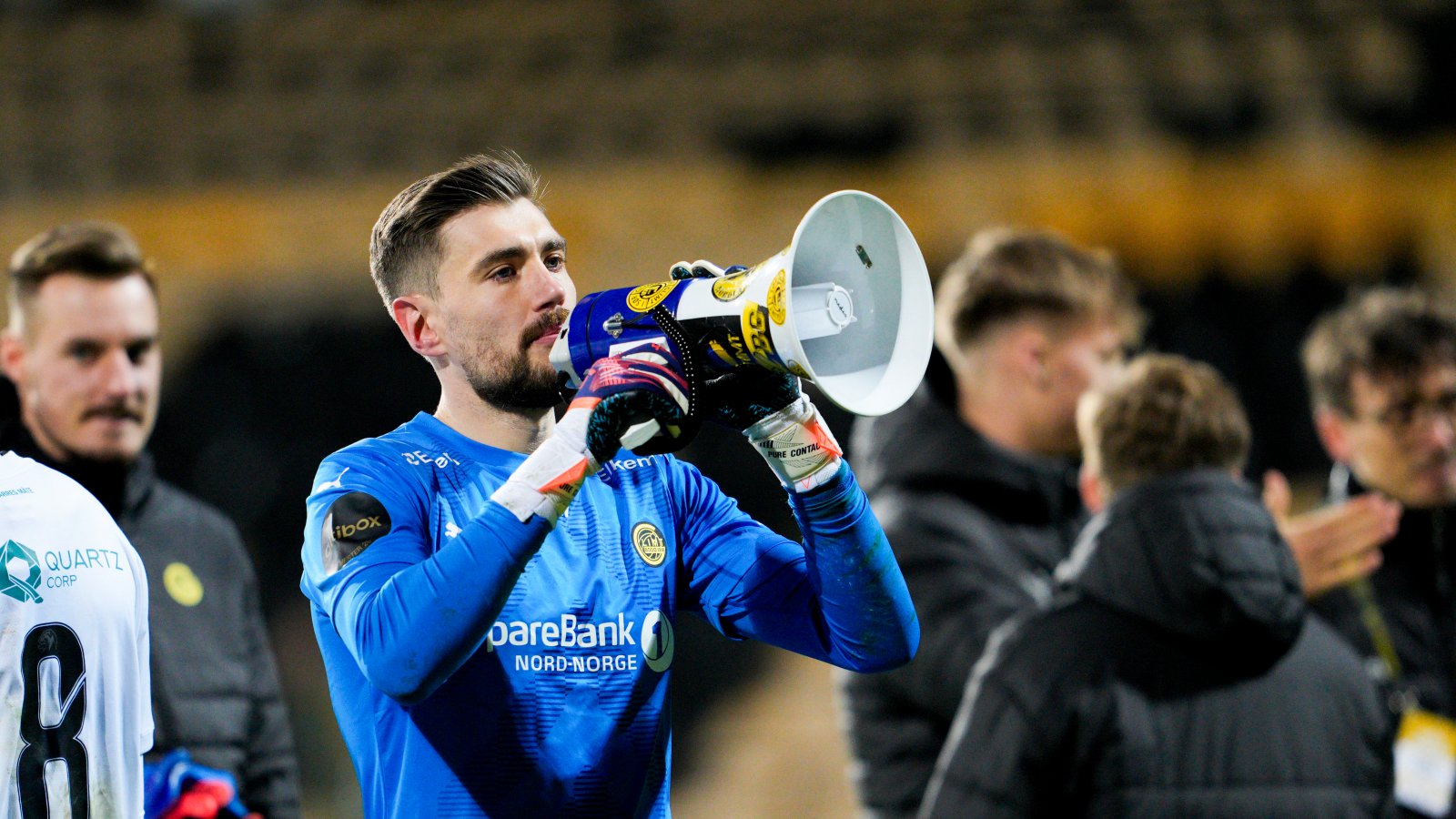 Nikita Haikin i blå keeperdrakt med megafon i hånden etter 5-0-seieren på Åråsen i april 2024. Sammen med lagkameratene feiret han tre poeng med supporterne.