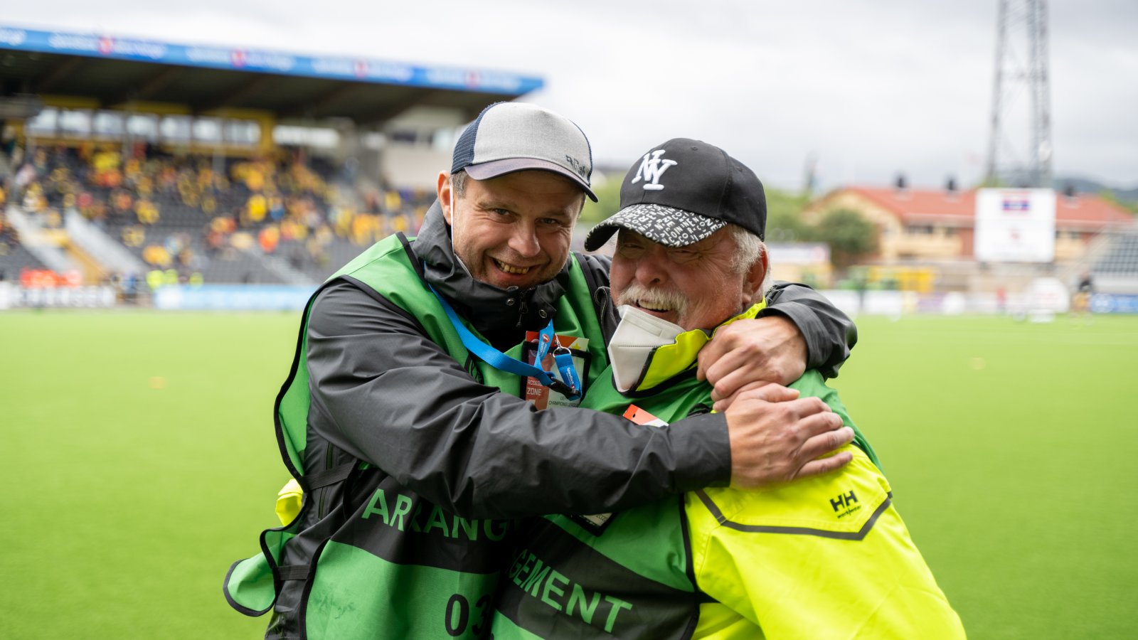 Stian fra Glimtvis og Thor Lihall under kampen mot Linfield på Aspmyra 2022. I grønne vester med akkreditering.